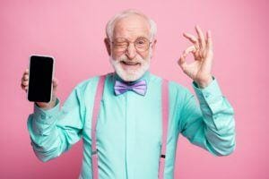 Portrait of energetic positive old man holding new cellphone
