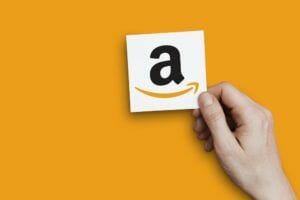amazon logo held up by a hand on an orange background