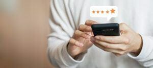 a person's hands hold a smarthone with a 5 star google review popping over the screen